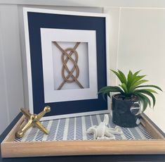 a cross, potted plant and framed artwork on a table