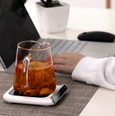 a glass mug sitting on top of a table next to a cell phone