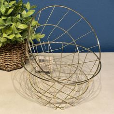 two wire baskets sitting on top of a table next to a basket with a plant in it