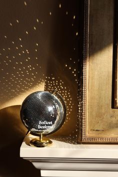 a disco ball sitting on top of a white shelf next to a framed painting and mirror