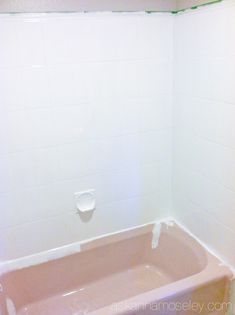 a bathtub in the corner of a bathroom with white tiles on the walls and floor