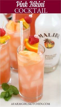 three glasses filled with pink drink and garnished with fruit on the rims