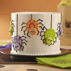 there is a decorated cake with spider decorations on the bottom and sides, along with green napkins