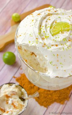 a close up of a cake in a glass on a wooden table with limes