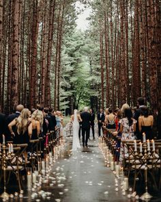 a bride and groom are walking down the aisle at their wedding ceremony in the woods