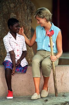 a woman sitting next to a man with a stick in his hand on the ground