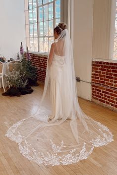 a woman in a wedding dress standing on a wooden floor with a veil over her head