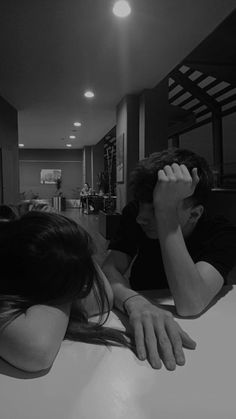 two people sitting at a table with their hands on their head