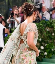 the back of a woman's dress as she walks down a street with cameras