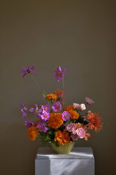 a vase filled with lots of colorful flowers on top of a white cubed container