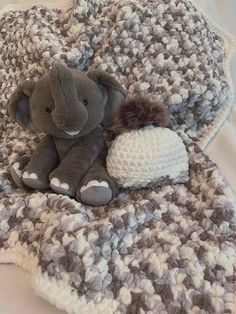 an elephant laying on top of a blanket next to a knitted beanie hat