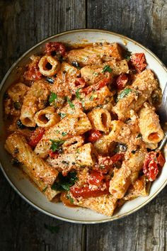 a bowl filled with pasta and sauce on top of a wooden table