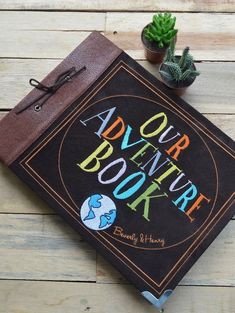 a book sitting on top of a wooden table next to a potted succulent