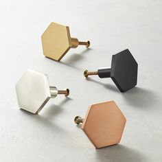 three different colored hexagonal knobs on a white surface with gold, silver and black handles