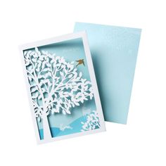 a card with a tree cut out of paper and a bird on the tree branch