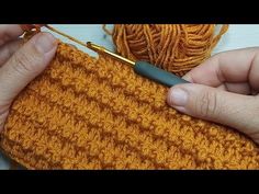 two hands crocheting the ends of a piece of orange yarn with a knitting needle