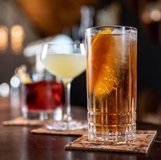 two glasses filled with drinks sitting on top of a wooden table next to each other