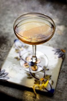 a close up of a drink in a glass on a table with a flower design