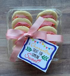 some cookies in a plastic container with a pink ribbon around the edge and a sign that says congratulations treat for someone sweet