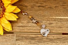 a heart shaped keychain sitting on top of a wooden table next to a sunflower