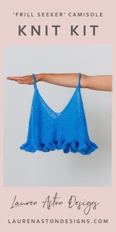 a woman's hand holding up a blue knitted tank top