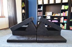 two black sculptures sitting in front of a book shelf filled with books and toys on top of carpeted flooring