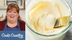 a woman is smiling and holding a spoon in front of a mixing bowl filled with cream