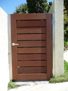 a close up of a wooden door on a concrete wall with grass and trees in the background