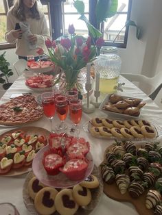 a table full of desserts and pastries with flowers in the vase on top