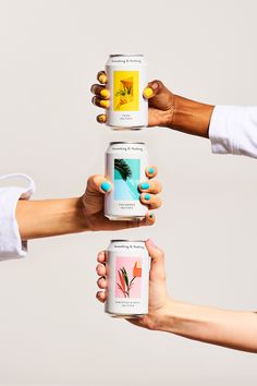 three women holding up cans of tea in the air with their hands on top of each other