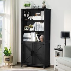 a black bookcase with doors and shelves in a living room next to a window