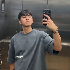 a young man taking a selfie with his cell phone in front of an elevator