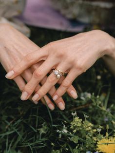 two hands holding each other in the middle of some grass and flowers with their fingers together