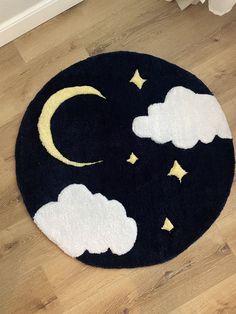 a black rug with white clouds and stars in the night sky on top of a wooden floor