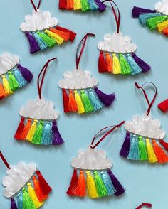 there are many rainbow decorations hanging on the wall in front of each other, including clouds and tassels