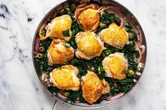 a pan filled with chicken and vegetables on top of a marble countertop next to utensils