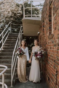 two women in long dresses standing next to each other on stairs with their bouquets