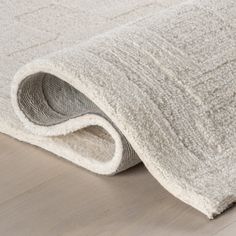 a white rug is laying on the floor next to a wooden floor with a light colored area rug