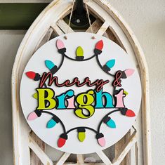 a merry and bright sign hanging from the side of a white building with lights on it