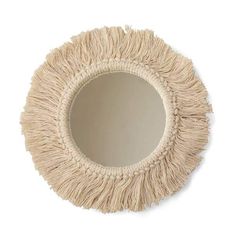 a round mirror with fringed edges on a white wall