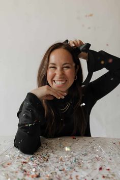 a woman sitting at a table with confetti all over her face and arms