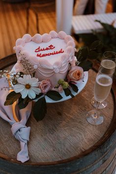 a heart shaped cake on a table with flowers and wine glasses in front of it