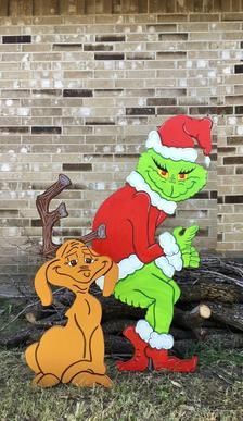 the grinch is sitting on top of a tree stump in front of a brick wall