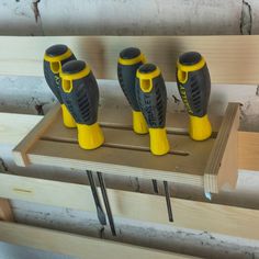 three yellow and black drillers sitting on top of a piece of wood