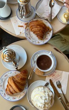 two plates with croissants and whipped cream on them sitting on a table