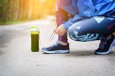 a person tying their shoelaces to a water bottle on the side of a road