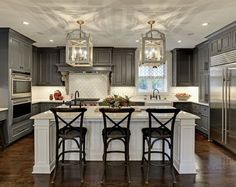 an image of a kitchen with gray cabinets and white counter tops, including the island