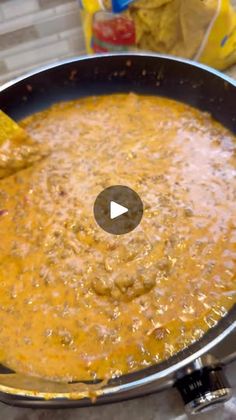 a pan filled with food sitting on top of a stove next to chips and cheese