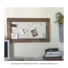 a bulletin board is hanging on the wall next to a computer and flower pot with yellow flowers