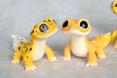 two yellow and black geckos sitting next to each other on a gray surface